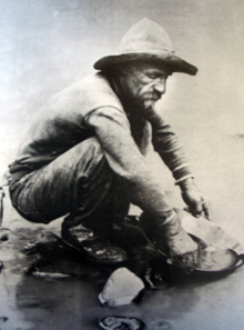 A gold prospector panning the precious metal using the gold pan.