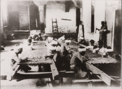 Photograph showing artisans at work at Dar al-Kiswah. 8.8 x 12 cm. Nasser D. Khalili Collection of Islamic Art © Nour Foundation. Courtesy of the Khalili Family Trust.