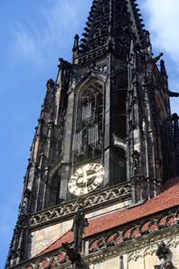 Tower of St. Lambert's Church, Münster. Above the clock three iron cages are suspended in which the corpses of the executed Anabaptists had been put on display. Photograph: Wikipedia / Jule Hintzbergen. CC-Lizenz 3.0.