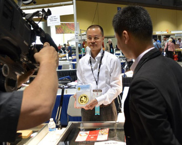 Mr. Chen Haomin, Chairman of Coin in Coin, Guangzhou, China and General Manager of the Guangzhou PCGS Submission Center, holds a PCGS-certified 1996 China Unicorn 1 kilo gold coin during an interview with a Los Angeles television station during the June 2014 Long Beach Expo./ Photo credit: Donn Pearlman.