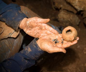 A photograph taken in the cave: agate stones that were part of a string of beads and the Hellenistic oil lamp in which the stones were kept. Photograph: Shmuel Magal. Courtesy of the Israel Antiquities Authority.