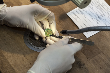 Coin restoration under the binocular. © Canton of Aargau. Photograph: Béla Polyvŕs.