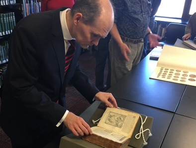 Dr. Woytek examining a 1567 edition of works by Guillaume Du Choul.