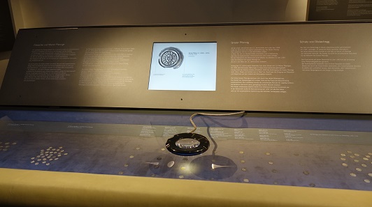 Big magnifying glasses not only enable visitors to get a larger image of the coins in the vitrines, but they are also presented with additional information of a screen. Photo: KW.