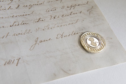 Jane Austen coin against Jane Austen’s signature on her will. Photo: Courtesy of The National Archives, Kew.