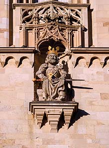 Fig. 4: Copy of the statue of Charlemagne on the southern tower of the Grossmünster
(the original can be seen in the crypt). Native citizens of Zurich will tell you that this stone statue will throw bread from the tower of the Grossünster as soon as he hears the 6th stroke of the church?s bell. This is absolutely true. Or would you believe a stone statue being able to hear? Foto: roland, zh / Wikipedia