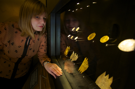 Dr Megan Gooch looks at a case of rare coins at the launch of the new exhibition. © Historic Royal Palaces.